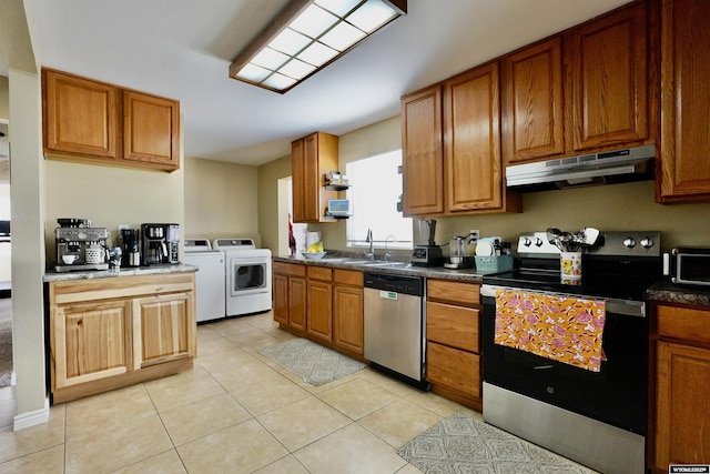 kitchen with independent washer and dryer, a sink, stainless steel appliances, under cabinet range hood, and brown cabinets