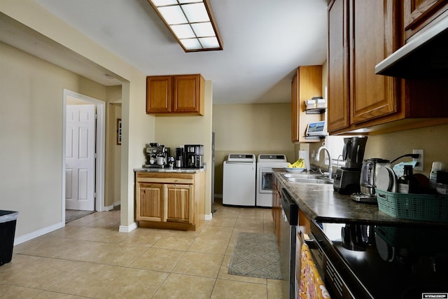 kitchen featuring under cabinet range hood, washing machine and dryer, light tile patterned floors, brown cabinets, and a sink