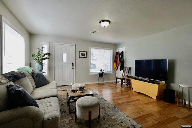 living room featuring wood finished floors, visible vents, and baseboards