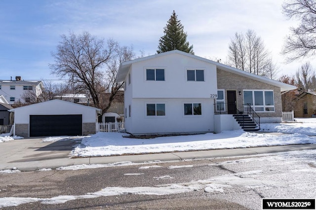 view of front of house with a detached garage, an outdoor structure, and fence