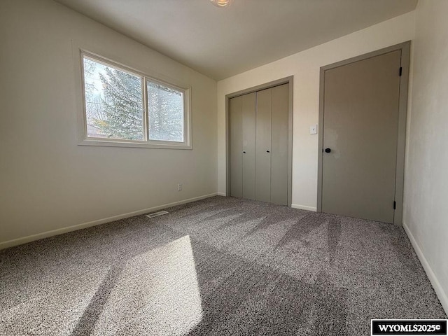 unfurnished bedroom with a closet, visible vents, baseboards, and carpet floors