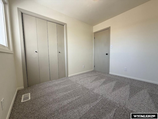 unfurnished bedroom with baseboards, visible vents, carpet floors, and a closet