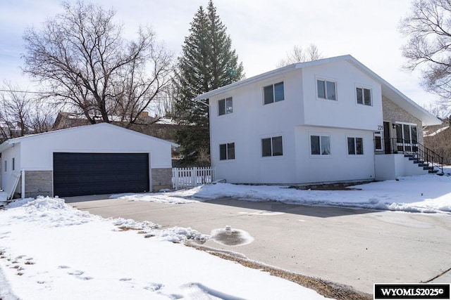 view of front of house featuring an outbuilding, fence, a detached garage, and stucco siding