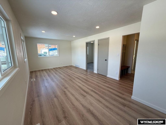 unfurnished bedroom featuring recessed lighting, baseboards, a textured ceiling, and wood finished floors