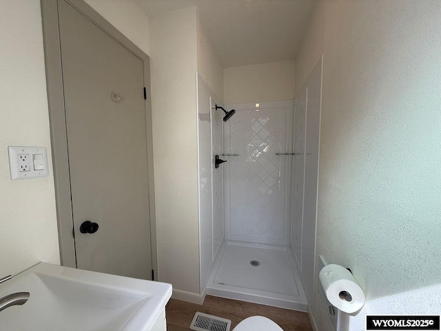 full bathroom featuring visible vents, wood finished floors, walk in shower, and a sink