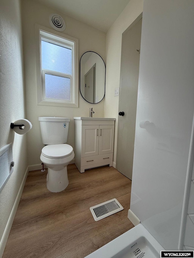 bathroom with vanity, wood finished floors, visible vents, baseboards, and toilet