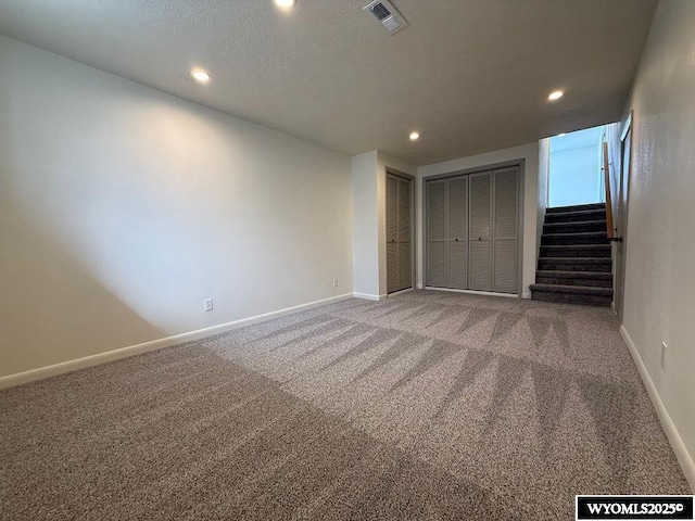 unfurnished bedroom featuring carpet flooring, baseboards, visible vents, and multiple closets