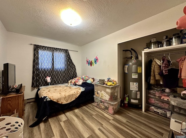 bedroom featuring a textured ceiling, wood finished floors, water heater, a closet, and baseboard heating