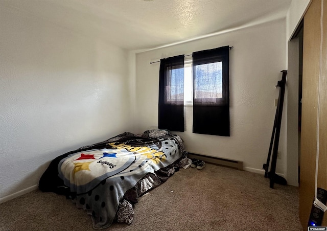 carpeted bedroom featuring baseboard heating and a textured wall