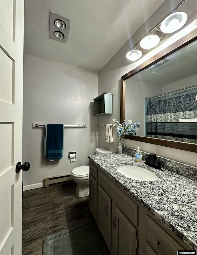 full bath featuring toilet, a baseboard heating unit, a textured ceiling, wood finished floors, and vanity