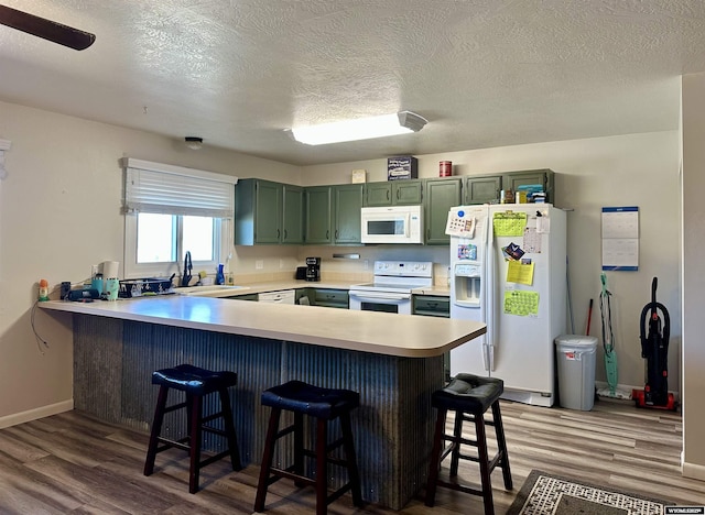 kitchen featuring white appliances, dark wood-style floors, a peninsula, and green cabinetry