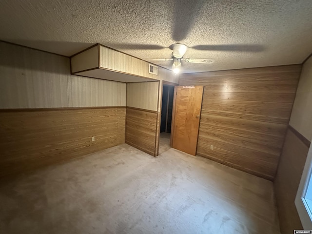 unfurnished bedroom with wooden walls, visible vents, concrete floors, and a textured ceiling