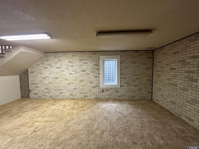 additional living space with carpet, brick wall, and a textured ceiling