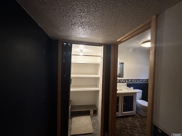 bathroom with toilet, vanity, and a textured ceiling