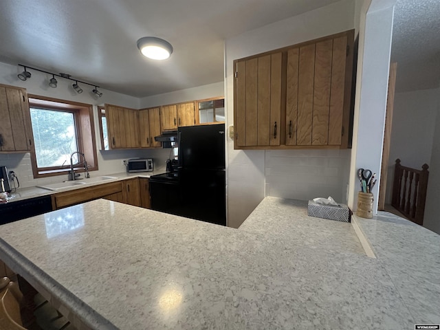 kitchen with extractor fan, light countertops, a peninsula, freestanding refrigerator, and a sink