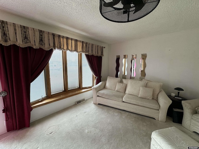 carpeted living room with visible vents and a textured ceiling