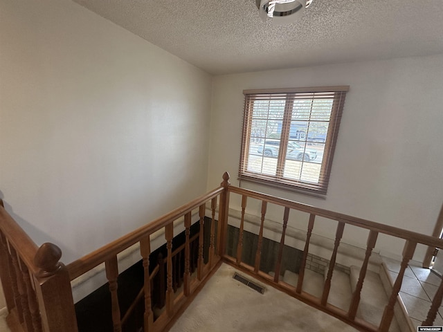 stairway with visible vents and a textured ceiling