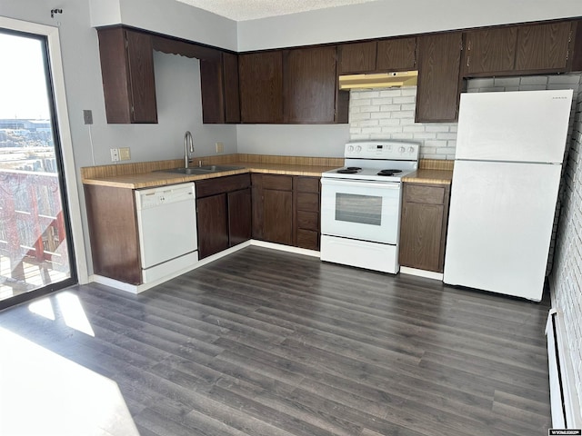 kitchen featuring dark wood finished floors, under cabinet range hood, light countertops, white appliances, and a sink