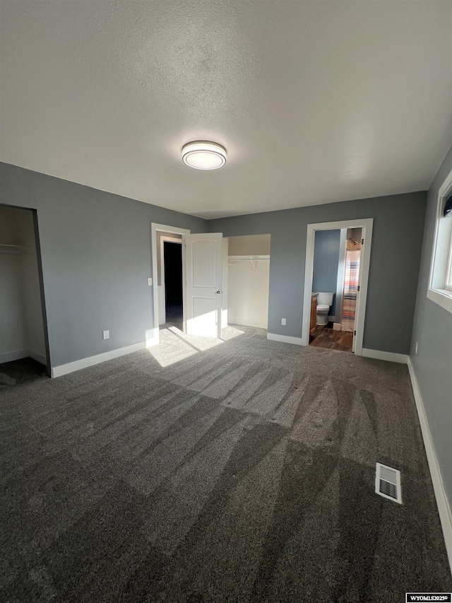 unfurnished bedroom with visible vents, baseboards, a textured ceiling, and carpet flooring