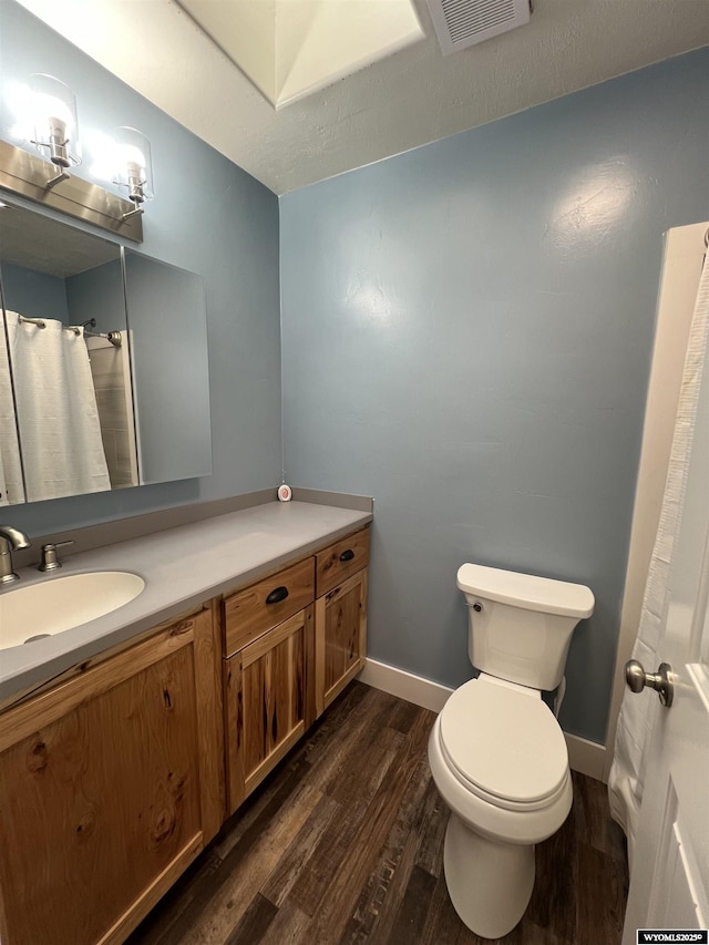 full bath with vanity, wood finished floors, visible vents, baseboards, and toilet