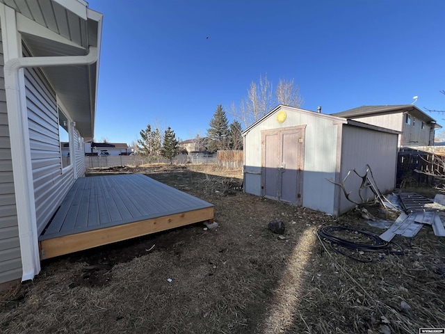 view of yard featuring a deck, an outbuilding, fence, and a shed