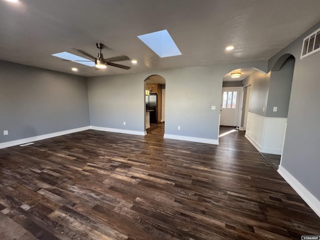 empty room featuring visible vents, a ceiling fan, recessed lighting, arched walkways, and dark wood-style flooring