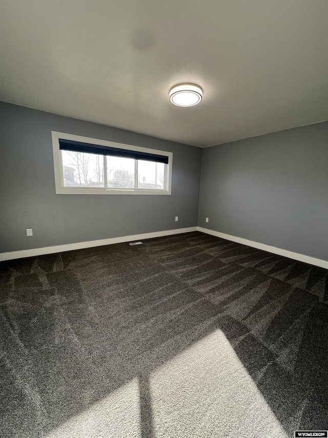 spare room with a healthy amount of sunlight, baseboards, and dark carpet