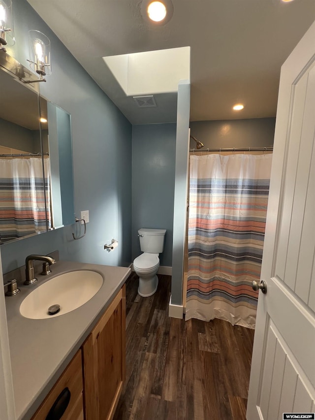 full bath with visible vents, toilet, curtained shower, wood finished floors, and vanity