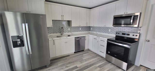 kitchen with stainless steel appliances, a sink, light countertops, and tasteful backsplash