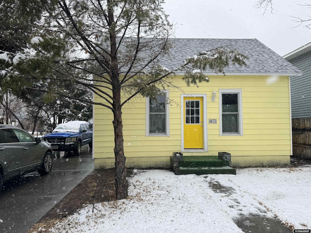 bungalow-style home with entry steps, a shingled roof, and fence