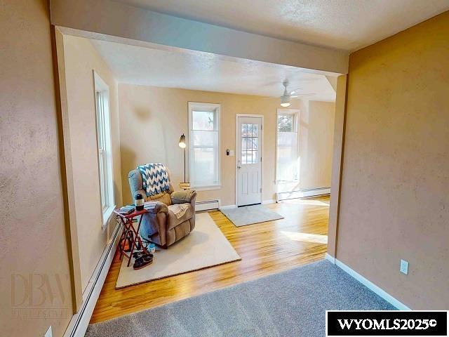 foyer with wood finished floors, a baseboard radiator, baseboards, and ceiling fan