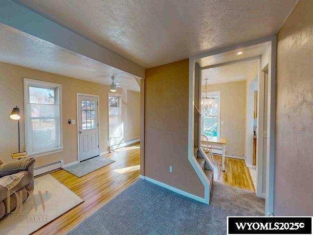 foyer featuring baseboards, a baseboard radiator, an inviting chandelier, a textured ceiling, and a baseboard heating unit