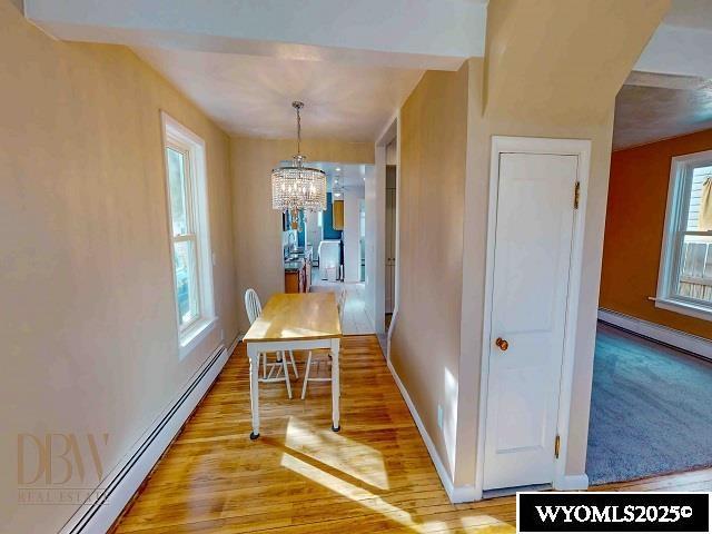 dining area with baseboards, baseboard heating, light wood-style floors, an inviting chandelier, and a baseboard radiator