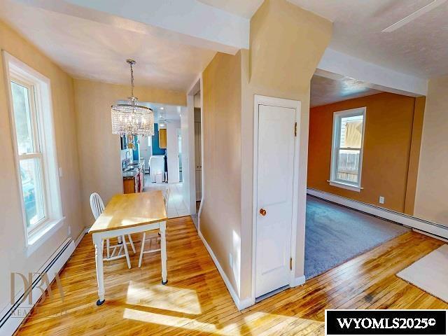 dining space with a notable chandelier, baseboard heating, light wood finished floors, and baseboards
