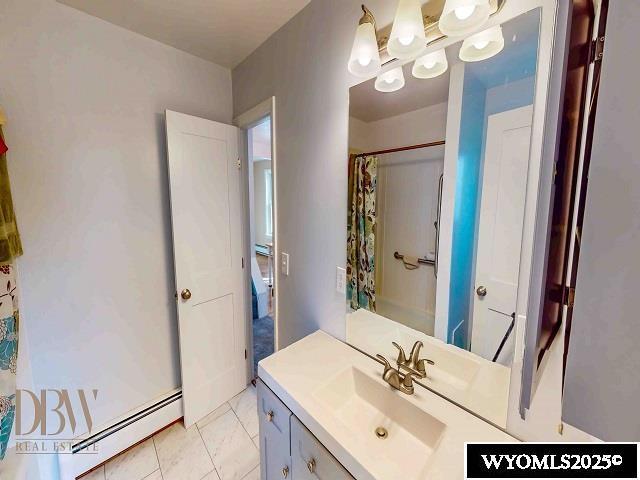 full bathroom with tile patterned floors, curtained shower, vanity, and a baseboard heating unit