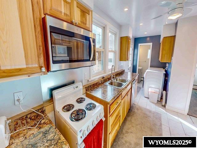 kitchen featuring white electric range oven, light tile patterned floors, a sink, dishwasher, and stainless steel microwave