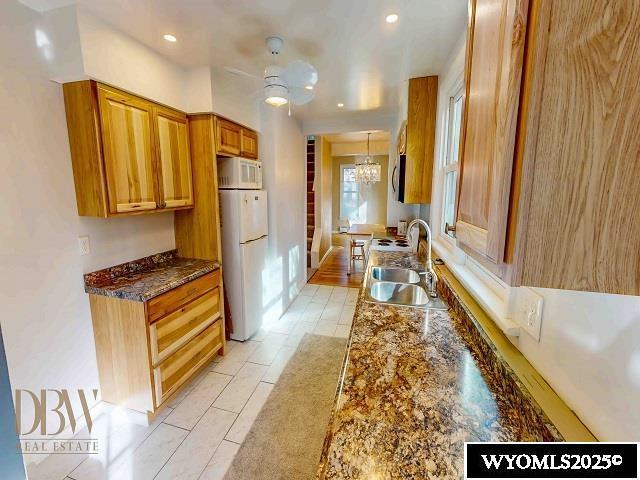 kitchen featuring a notable chandelier, a sink, recessed lighting, white appliances, and brown cabinetry