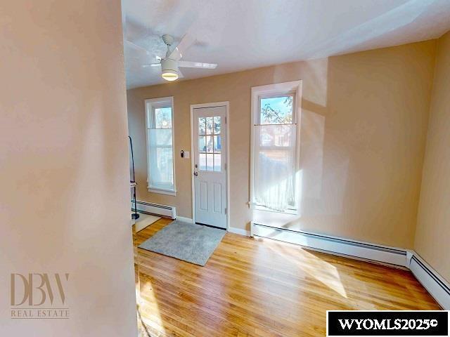 foyer entrance with a baseboard radiator, baseboard heating, wood finished floors, and a ceiling fan