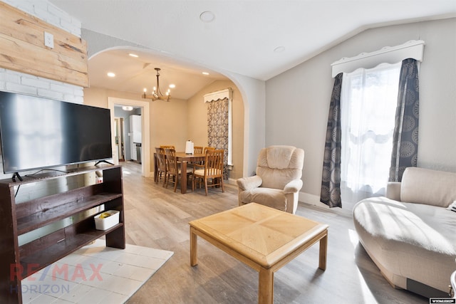 living room featuring lofted ceiling, recessed lighting, arched walkways, light wood-type flooring, and a chandelier