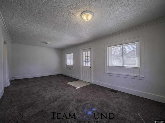 foyer entrance featuring visible vents, baseboards, dark carpet, ornamental molding, and a textured ceiling