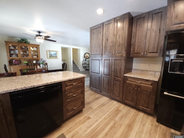 kitchen with light stone counters, a ceiling fan, light wood finished floors, black appliances, and dark brown cabinetry