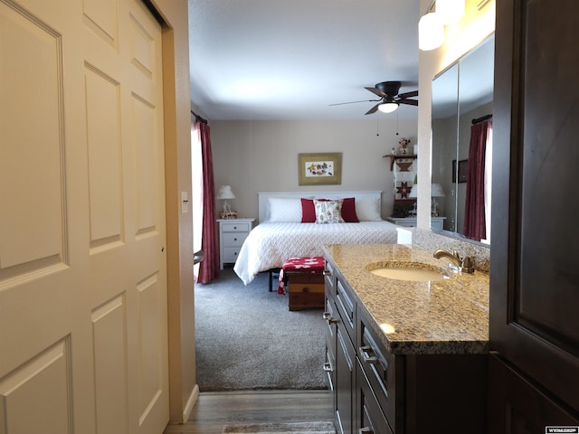 bedroom featuring a ceiling fan, dark wood-type flooring, dark colored carpet, and a sink