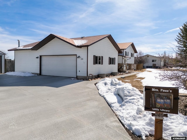 ranch-style house featuring an attached garage, concrete driveway, and fence