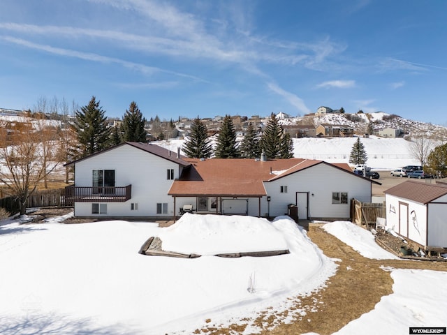 snow covered property with an outbuilding, fence, a garage, and a shed