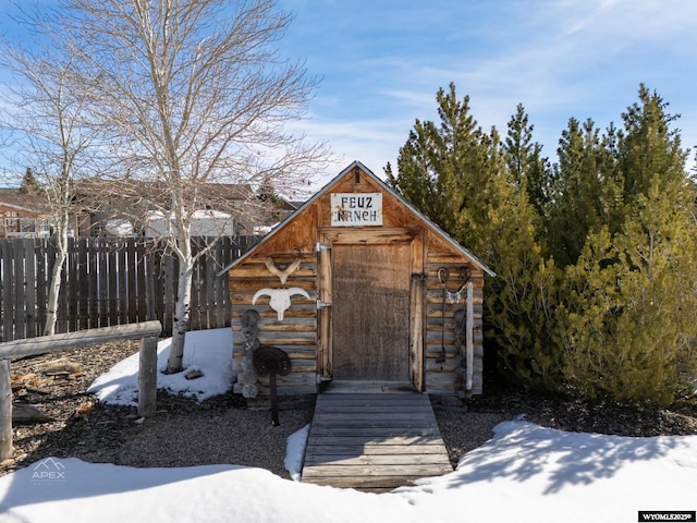 snow covered structure with an outdoor structure and fence