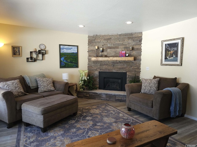 living room with a stone fireplace, recessed lighting, and wood finished floors