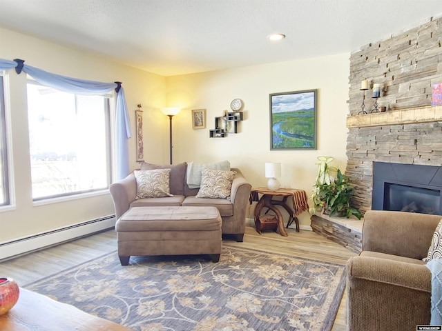 living area featuring a stone fireplace, a baseboard radiator, and wood finished floors