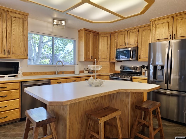 kitchen featuring a kitchen bar, a sink, a kitchen island, appliances with stainless steel finishes, and light countertops