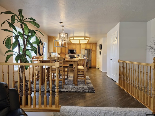 dining area with a textured ceiling and dark wood-style flooring