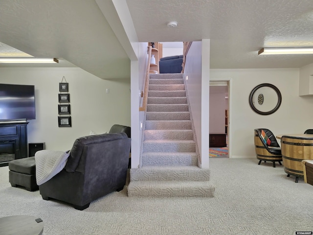 stairs with a glass covered fireplace, baseboards, carpet floors, and a textured ceiling